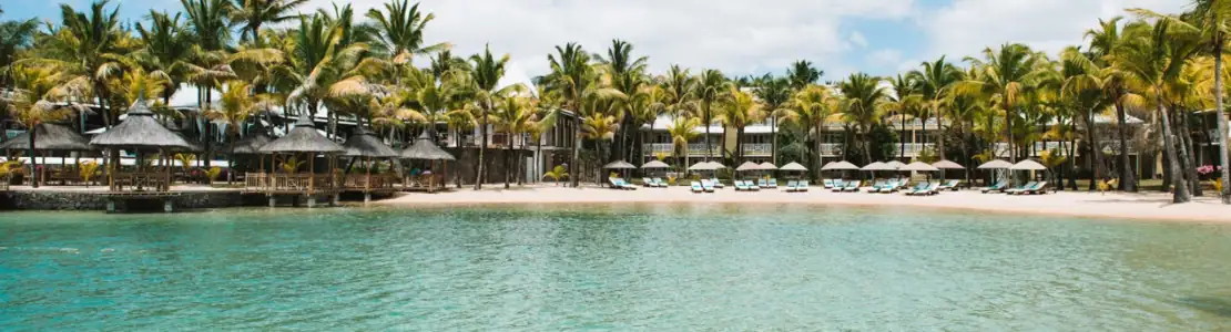 صورة: Paradise Cove Boutique Hotel: A turquoise pool fronts a sandy beach lined with palm trees, sun loungers, and thatched shade structures.