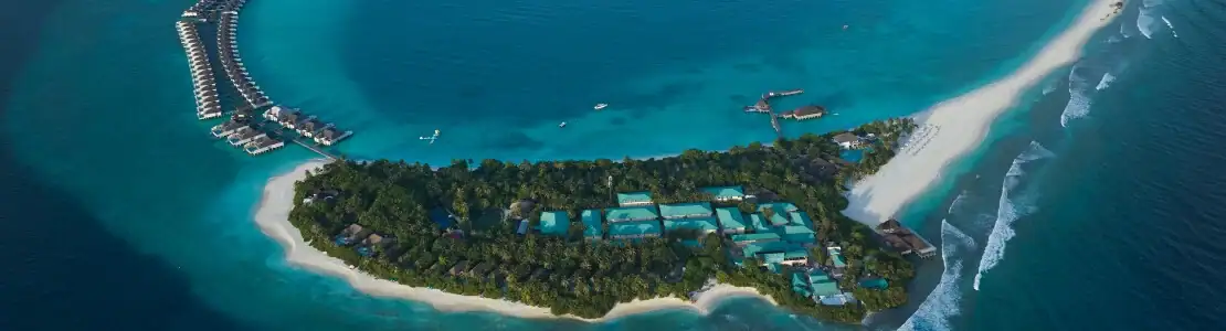 صورة: Finolhu, a Seaside Collection Resort: A tropical island resort surrounded by turquoise water, with white-sand beaches, lush greenery, and villas over the lagoon.