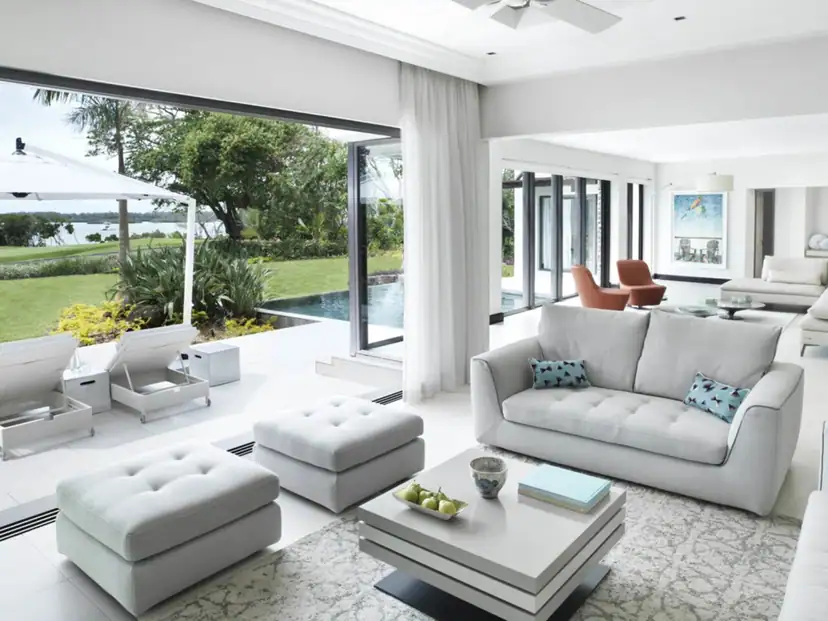 صورة: Four Seasons Resort Mauritius at Anahita: Bright living room opening onto a garden terrace with a pool and sun loungers.