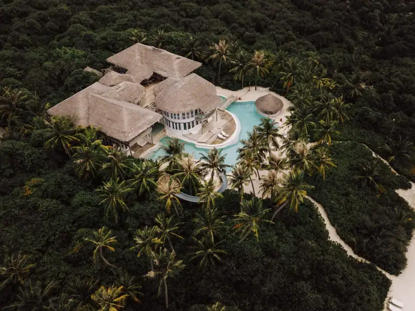 صورة: Soneva Jani: A sprawling thatched-roof beach villa sits among tropical palms, with a large swimming pool and curved water slide.