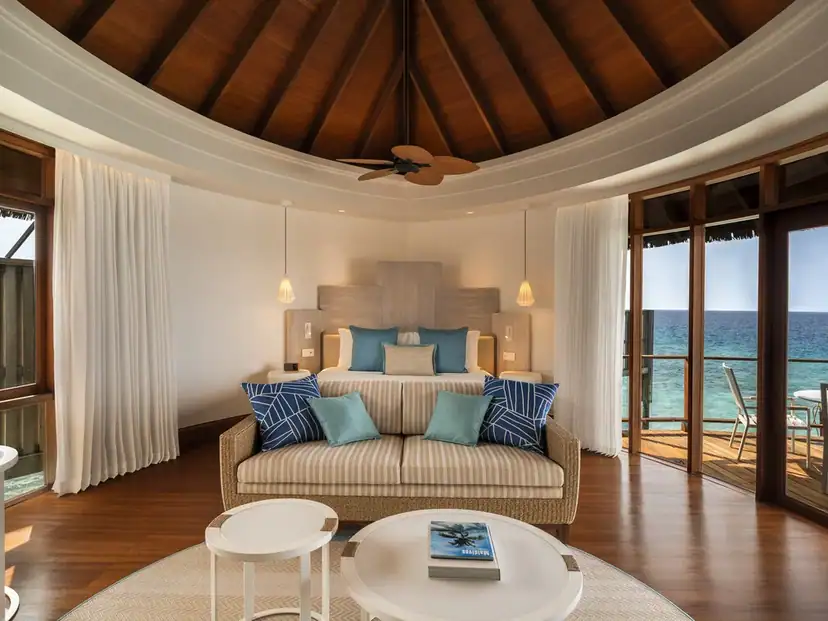 Constance Halaveli: A bright bedroom and lounge open onto a furnished oceanfront deck.