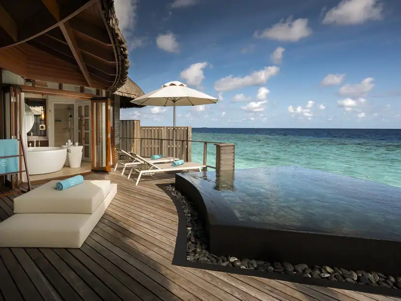 Constance Halaveli: A private pool and sun loungers overlook the ocean from a spacious wooden villa deck.