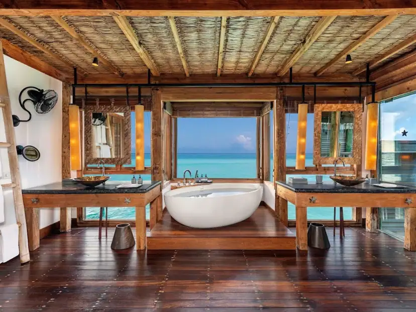 صورة: Gili Lankanfushi: A wood-finished bathroom with a freestanding tub overlooking turquoise ocean water and a double vanity.
